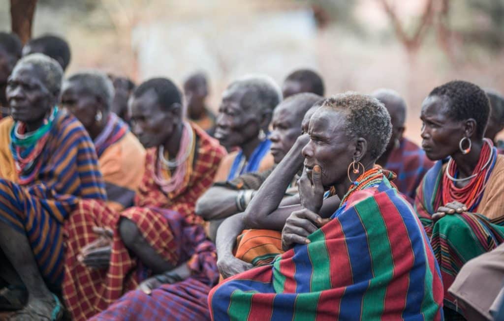 A group of Karamojong people sit listening to a Christian mission speaker in Uganda