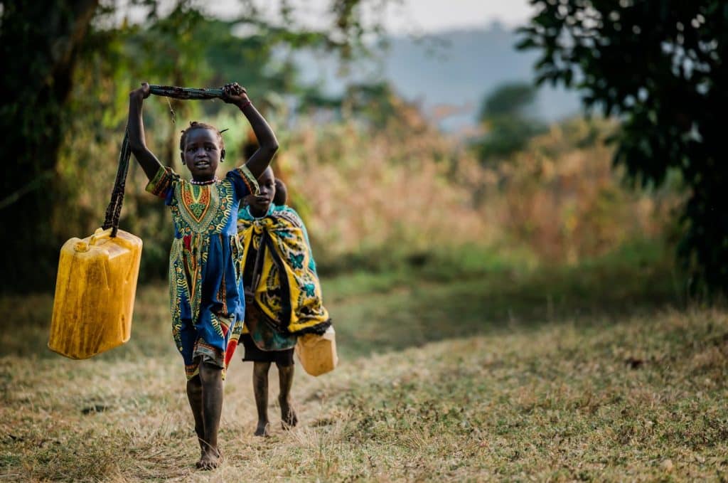 Didinga children walking along a path in South Sudan carrying jerrycans